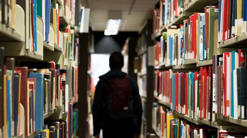 estudante em meio a biblioteca de livros